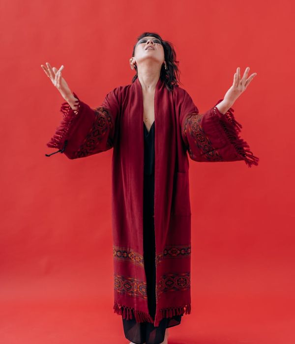 Elegant woman in a yoga pose against a rich maroon background.